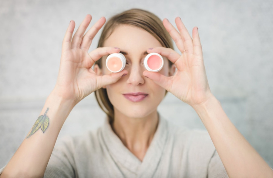 woman holding creams in front of her eyes